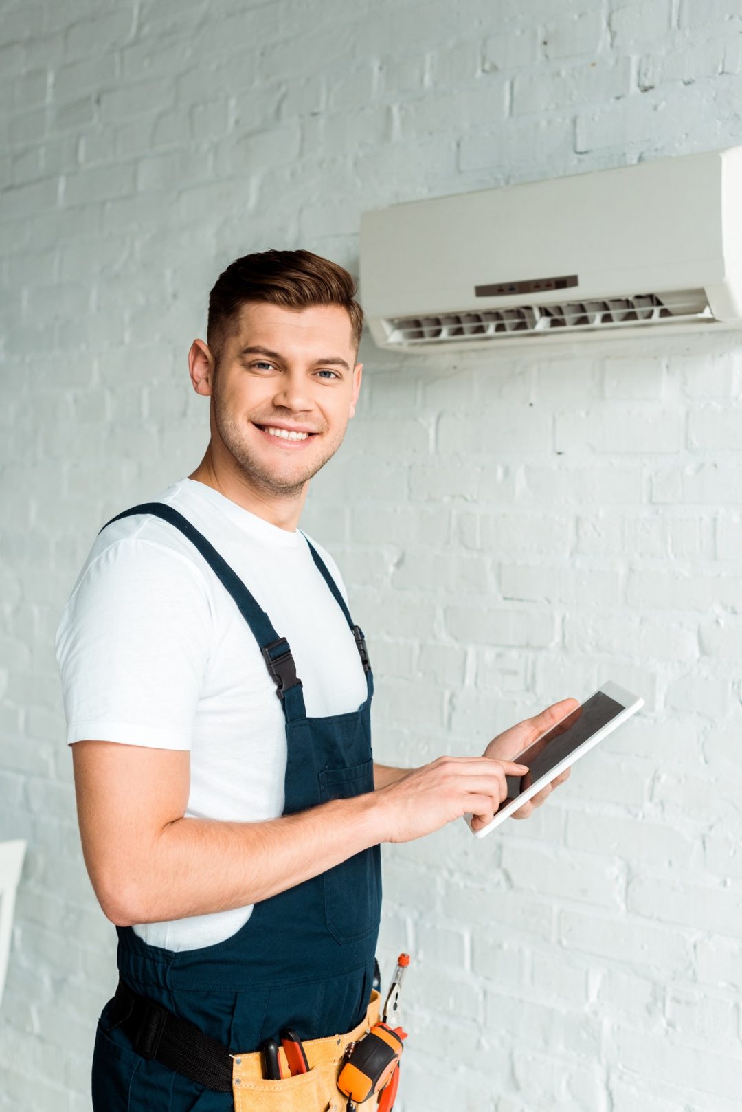 happy-installer-pointing-with-finger-at-digital-tablet-near-air-conditioner